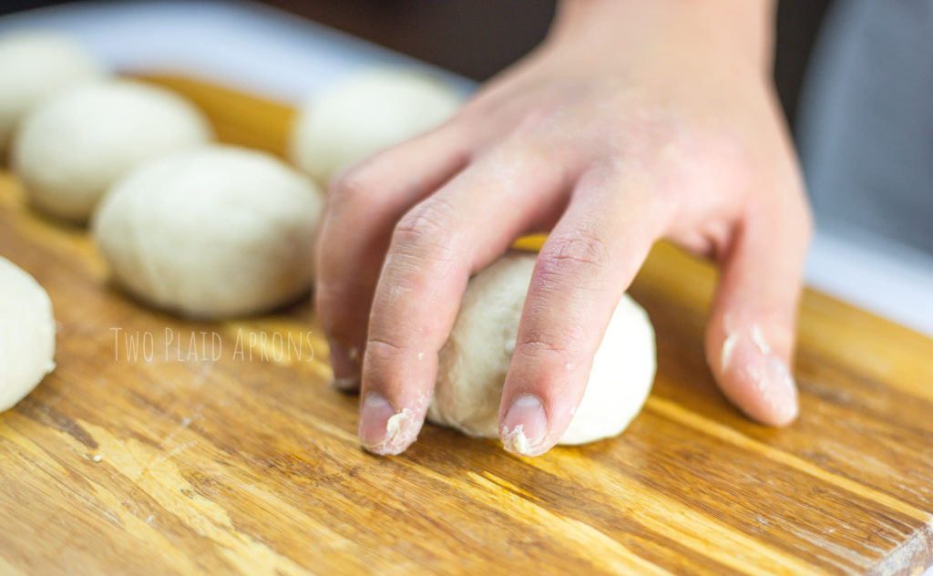 Rolling pita bread dough into individual balls.