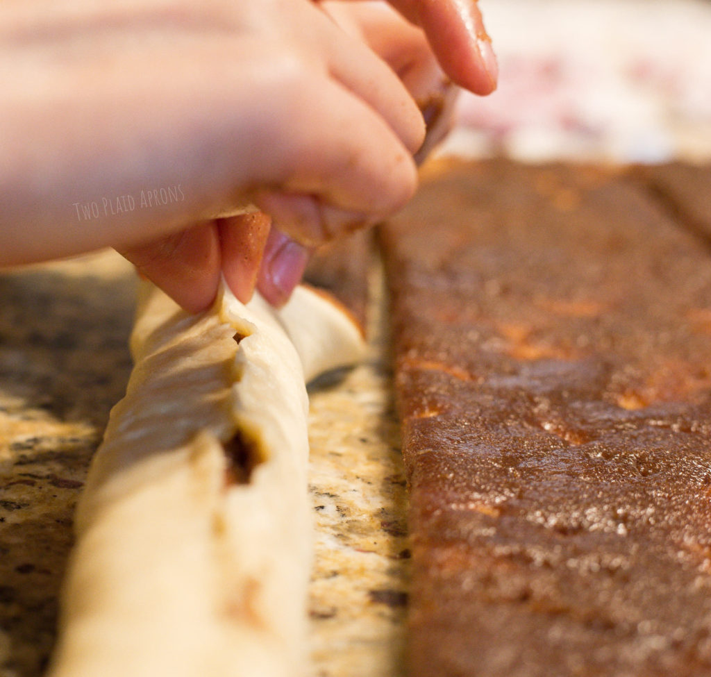 Pinching the seams of a rolled king cake dough together.