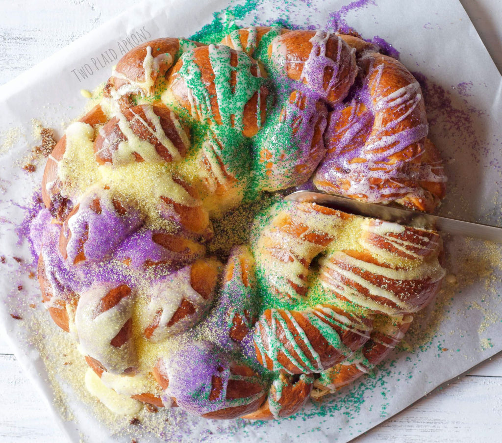 Cutting into an iced and decorated king cake.