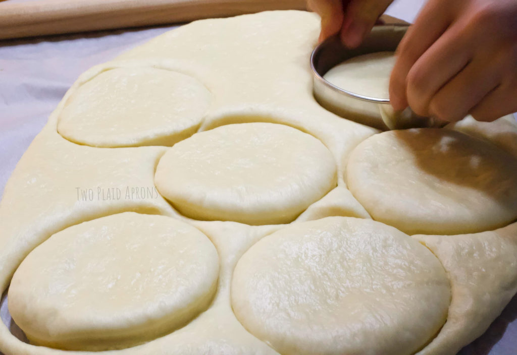 Cutting out circles of dough with a circle cutter.