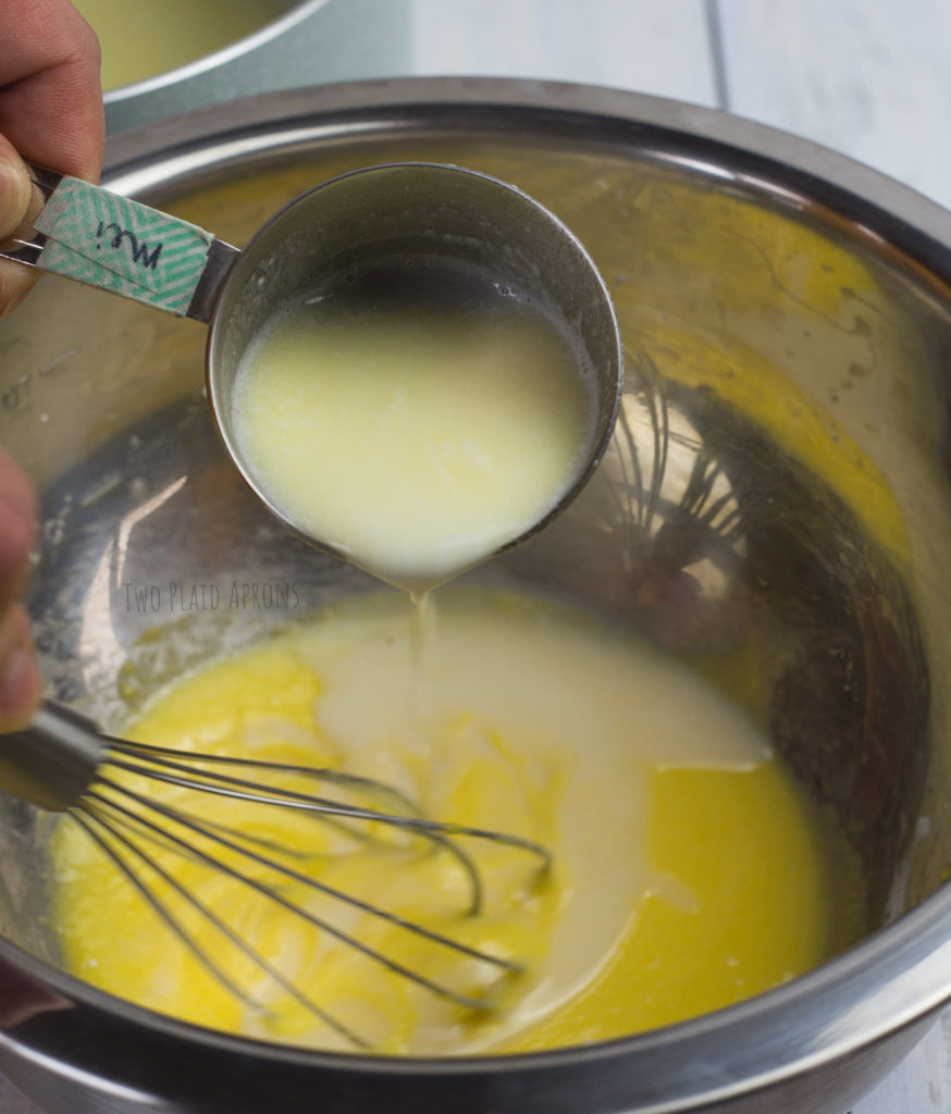 Tempering the egg mixture by streaming in a little hot milk at a time while whisking.