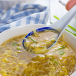 Holding a spoonful of egg drop soup above a bowl.