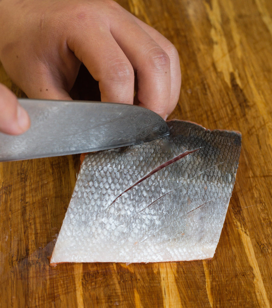Making shallow cuts on the salmon skin with a sharp knife.