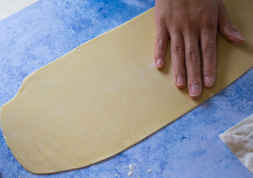 Flouring the sheet of dough in between rolling.