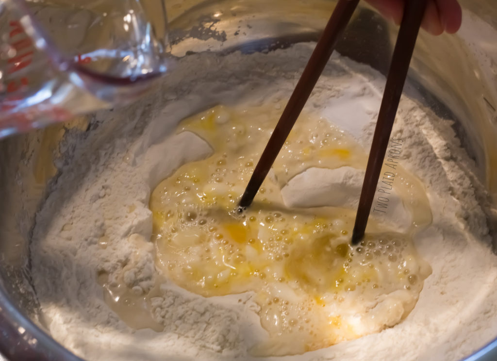 Using a pair of chopsticks to do the initial dough mixing.