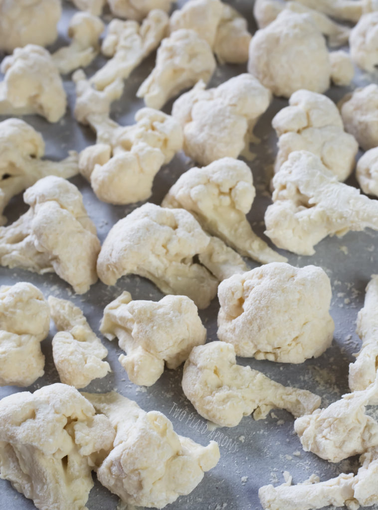 cauliflower florets dredged in the wet and dry batter on a lined sheet pan.