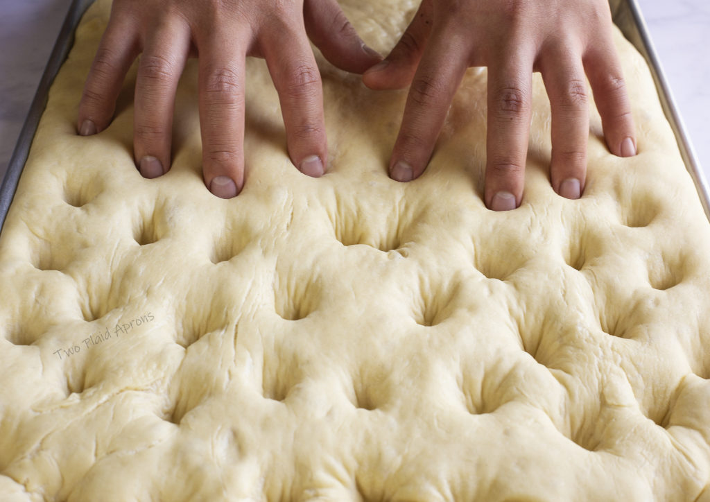 Using fingers make indentations in the focaccia dough.