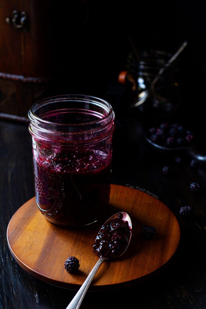 A glass jar of our easy blackberry compote with a spoonful on the side.