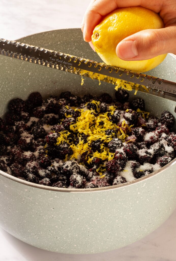 Zesting lemon zests into the blackberry mixture.