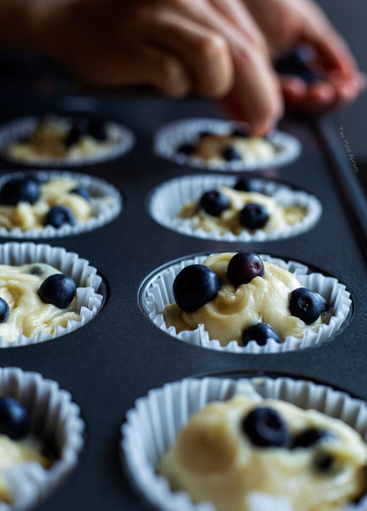 Topping the muffin batter with a few more fresh blueberries.