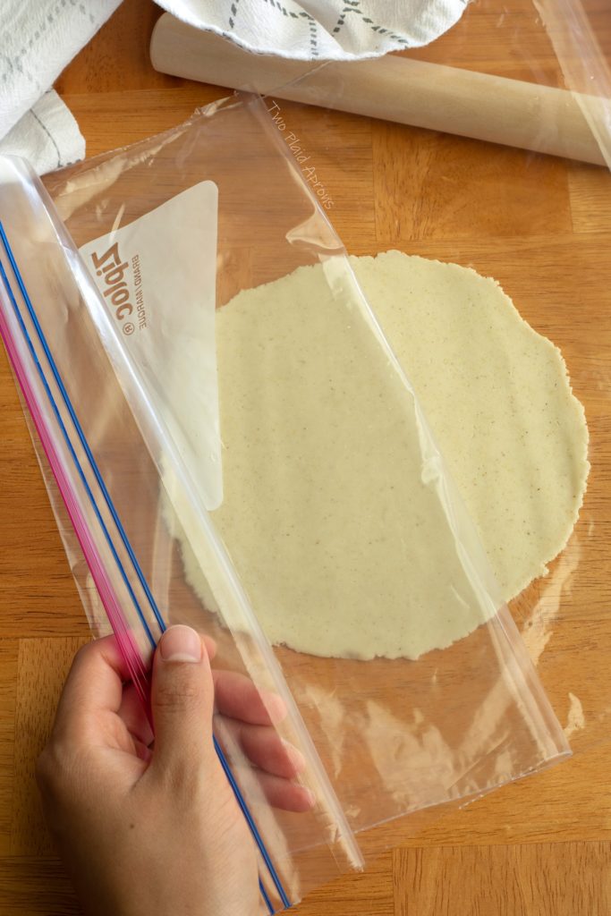 Peeling the plastic sleeve away from a rolled out tortilla.
