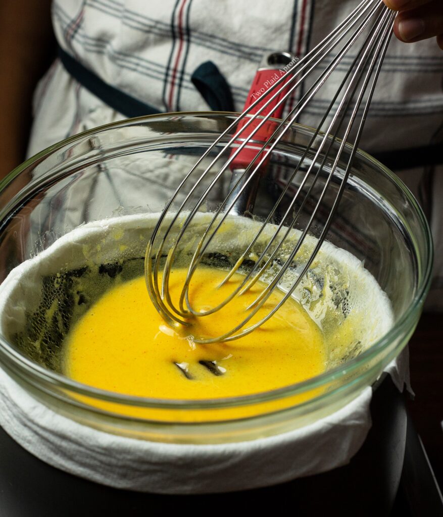 Whisking egg mixture in a bowl via bain marie.