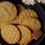 Close up, top view of a bowl of honey chrysanthemum shortbread cookies with a honey dipper.
