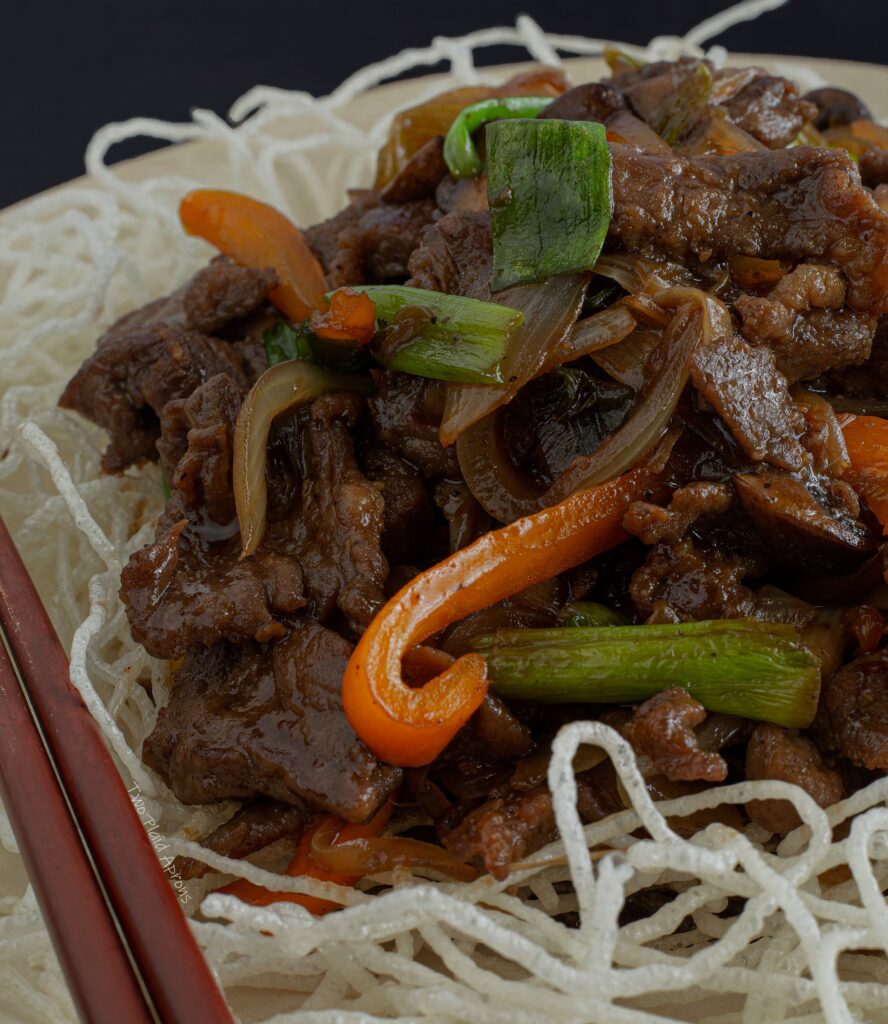 Side view of our restaurant style Mongolian beef on a bed of fried vermicelli.
