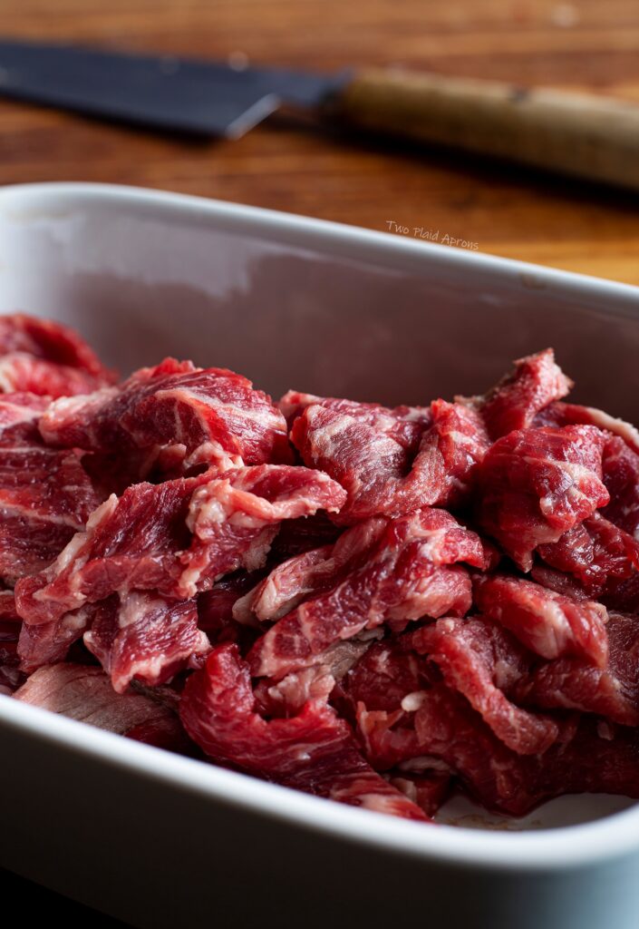 Beef cut into ⅛ inch slices in a bowl.