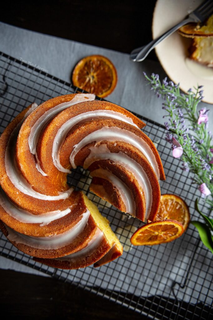 Top down view of orange olive oil cake on wire rack with candied oranges and decor.