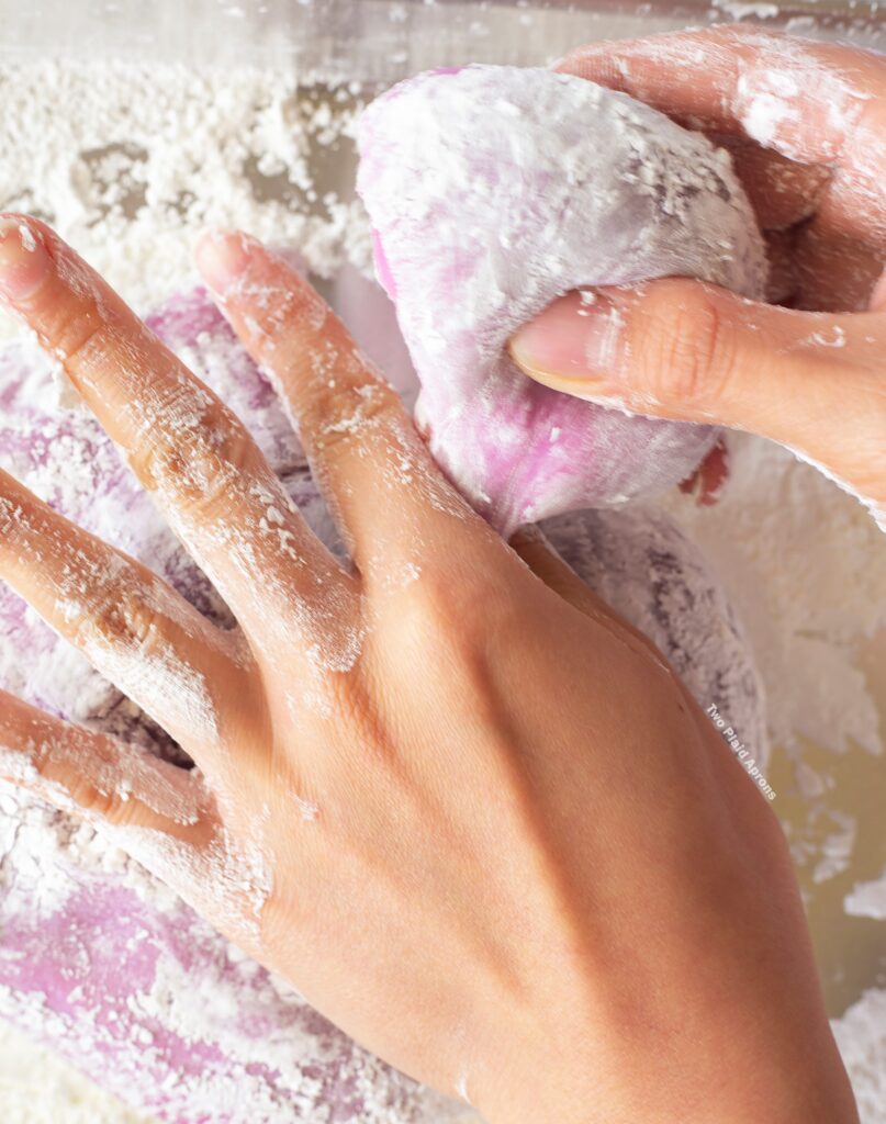 Portioning off a chunk of ube mochi by pinching the dough instead of pulling and tearing.