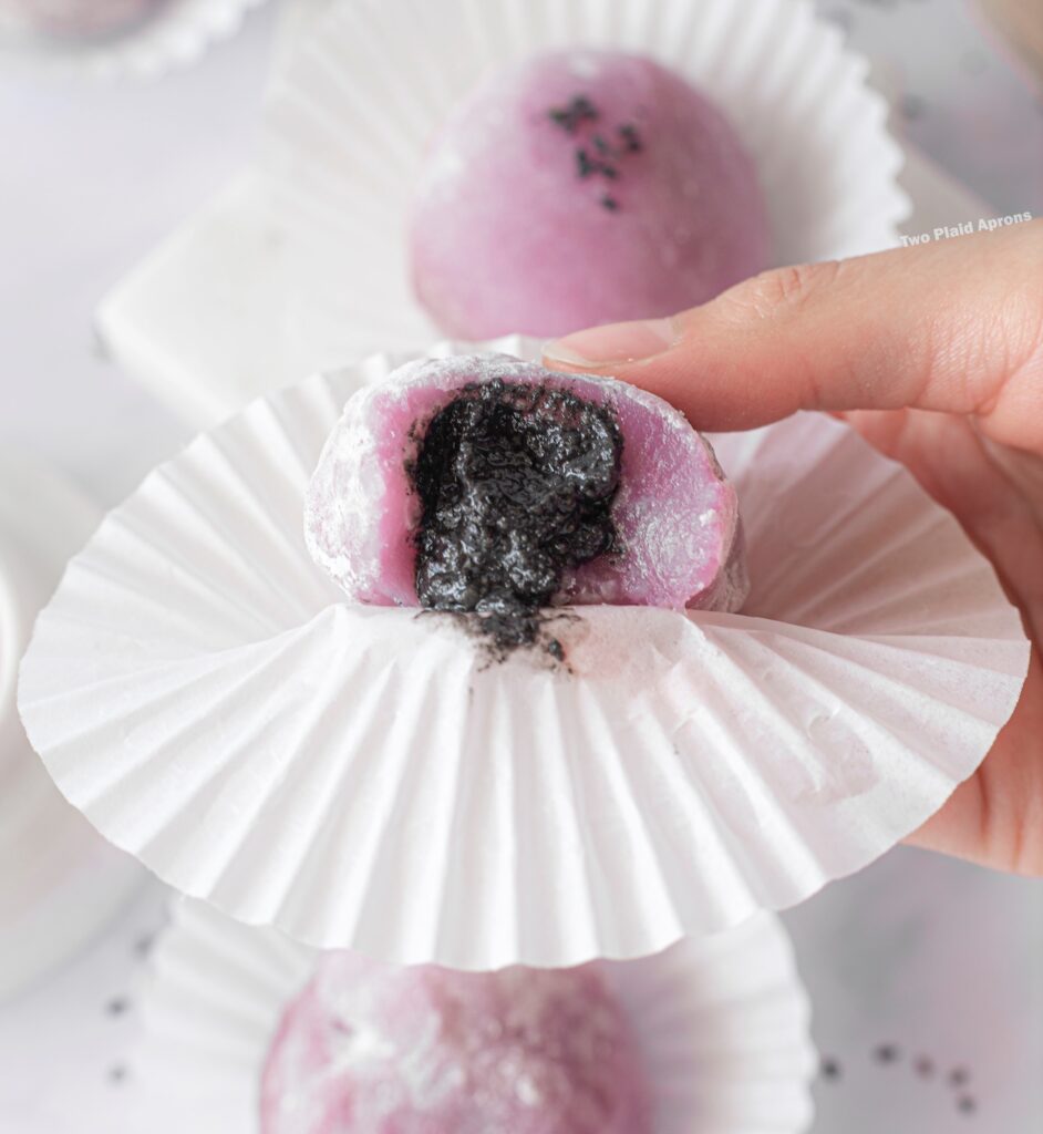Showing the interior of an ube mochi with black sesame filling up close.