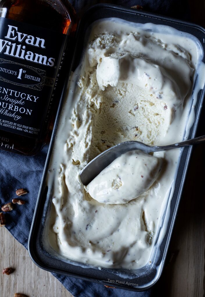 Top down of a scoop of bourbon pecan ice cream in a pan with Evan Williams bourbon on the left.