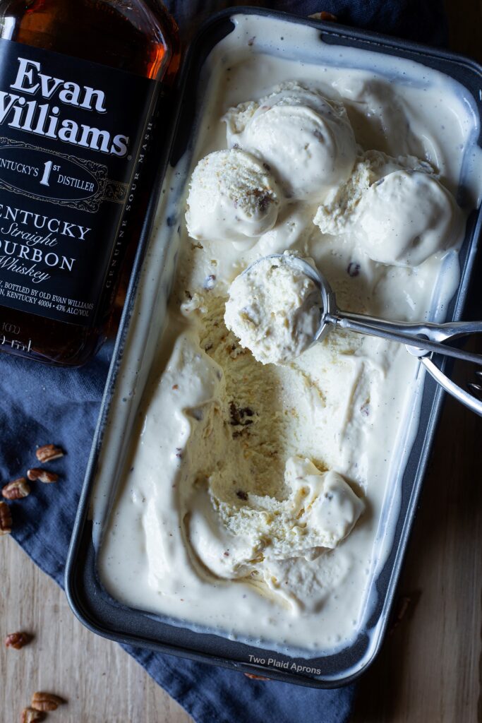 Top down view of scoops of bourbon pecan ice cream in a pan with Evan Williams bourbon on the left.