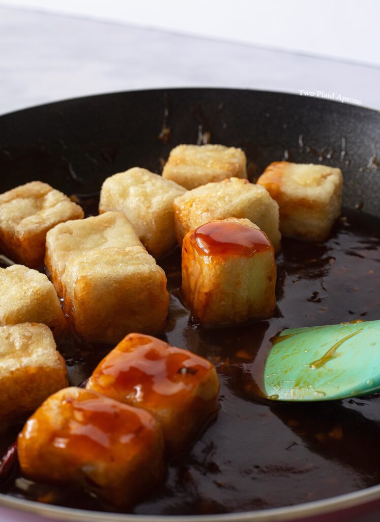 Tossing pan-fried tofu in General Tso's sauce.
