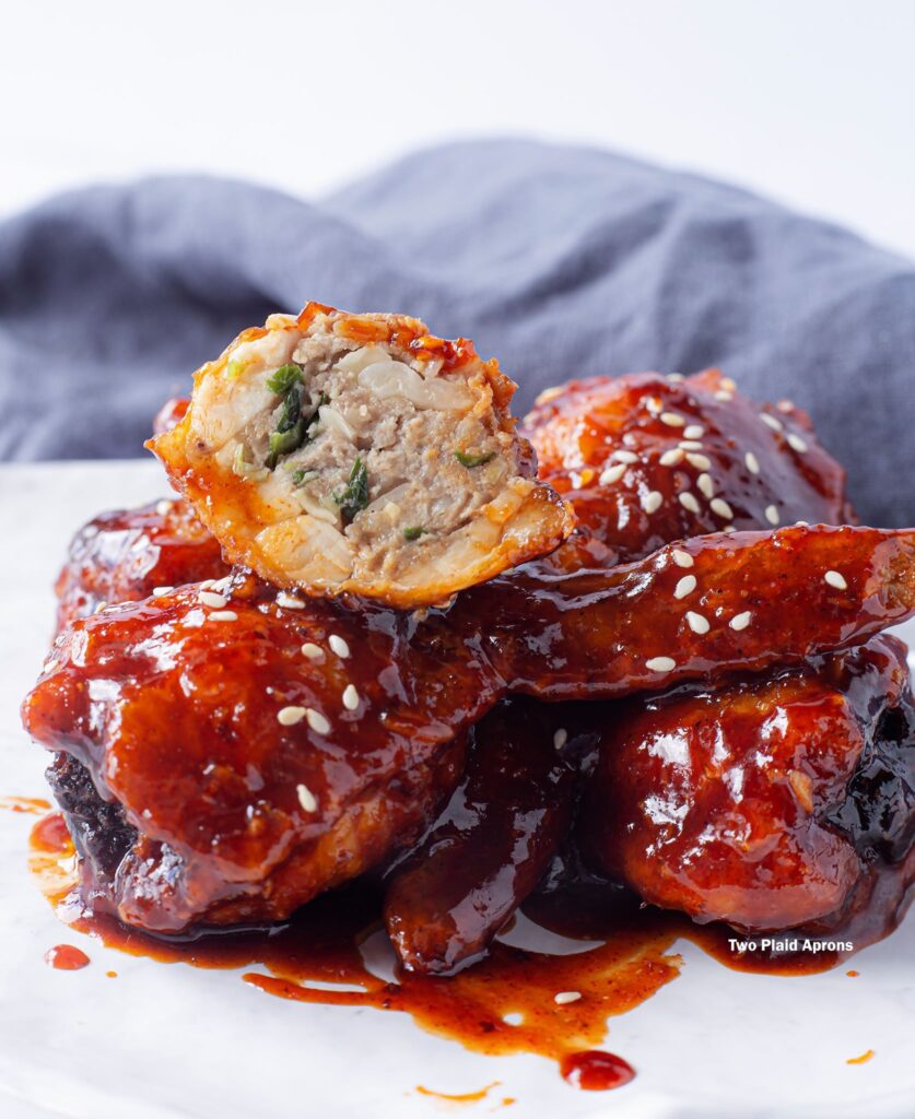 A plate of Korean Fried Chicken Wing Gyozas with one showing the interior.