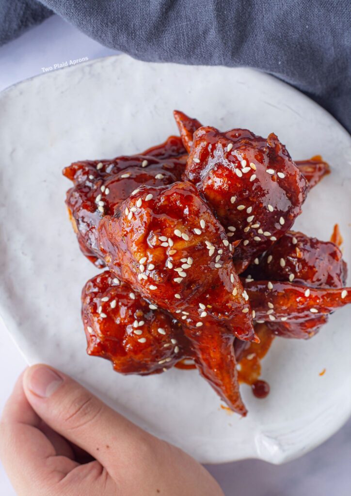 Holding a plate of Korean Fried Chicken Wing Gyozas.