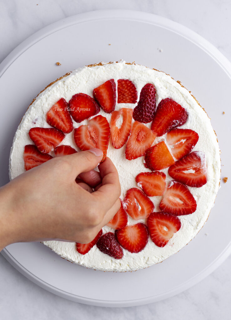 Placing sliced strawberries on the whipped cream layer.