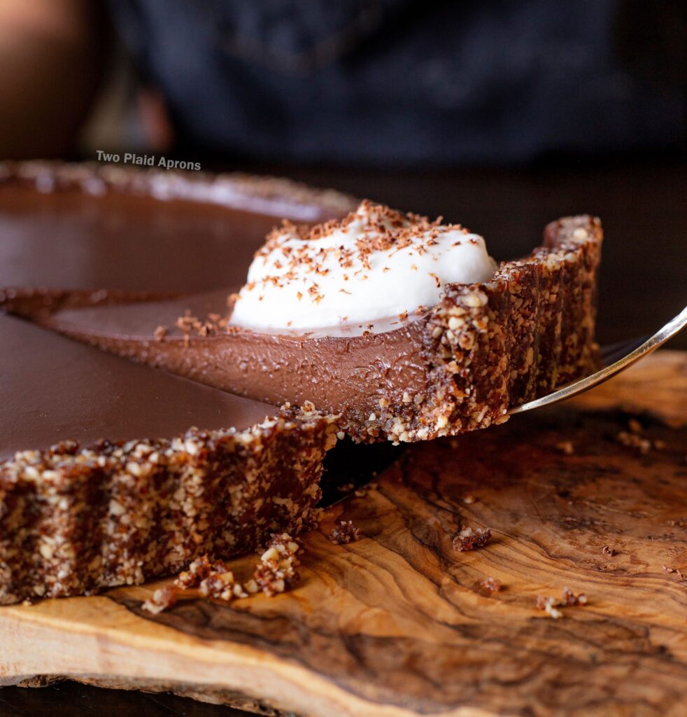 Lifting up a slice of no bake vegan chocolate tart.