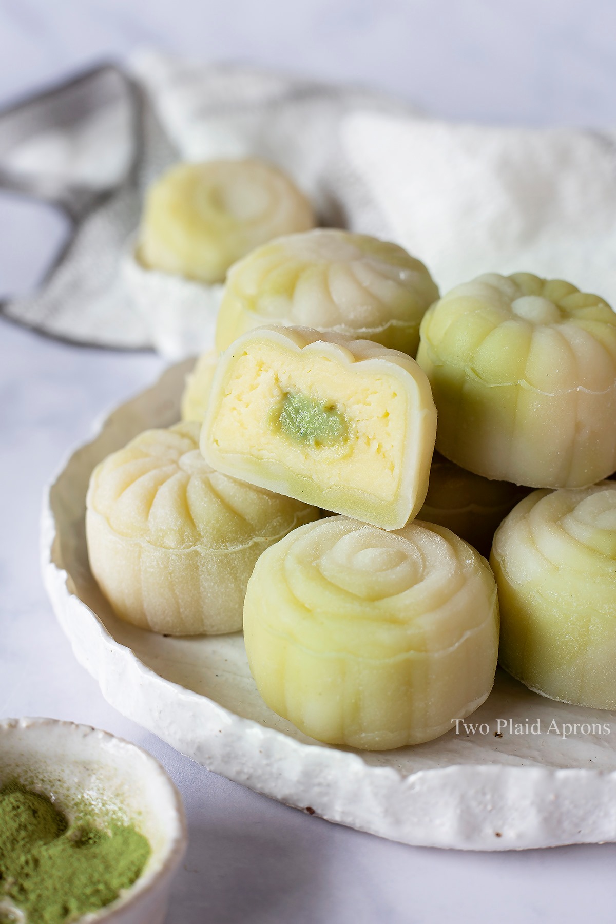 Front view of snow skin mooncakes with custard filling on a plate showing interior custard.