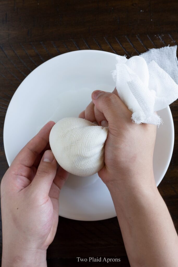 Squeezing tofu in cheese cloth to remove excess moisture.