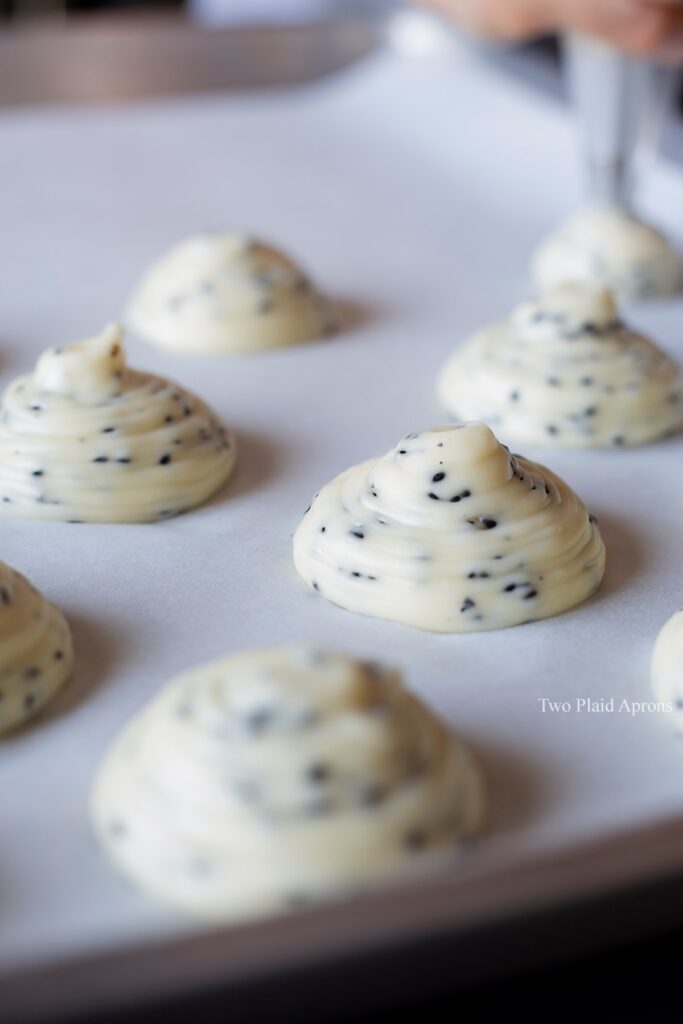 Piping mounds of the dough on a parchment lined sheet pan.