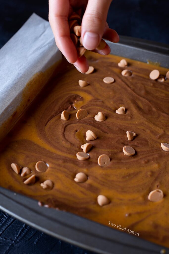Sprinkling butterscotch chips onto the brownie batter.