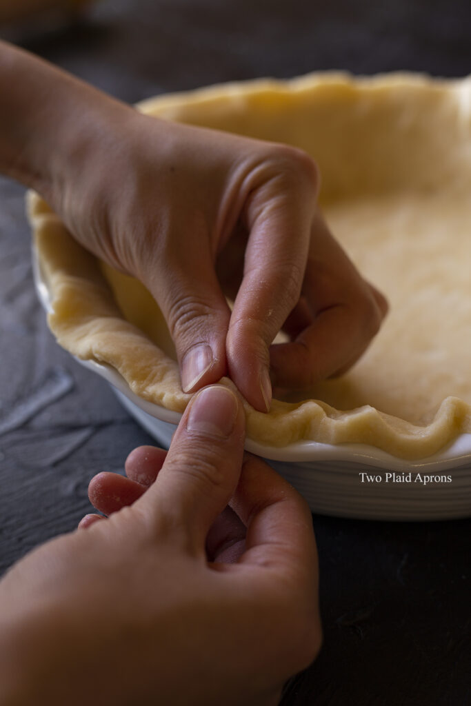 Crimping the crust by pressing the dough between the fingers.