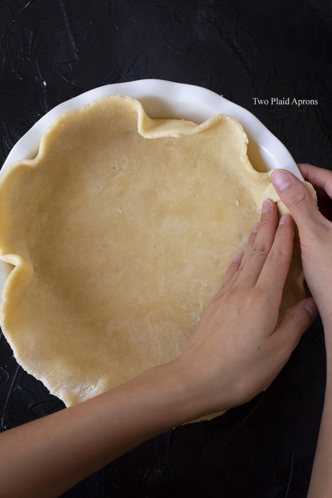 Gently pressing the crust in the pie pan.