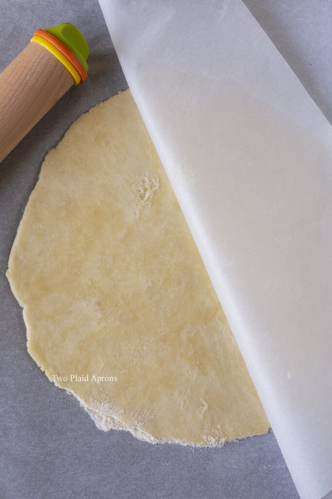 Peeling the rolled out crust from the parchment.
