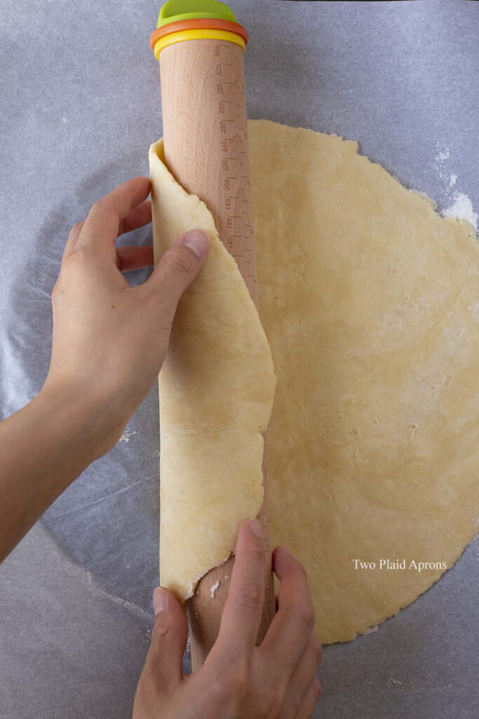 Rolling the dough over the rolling pin to place over the pie pan.
