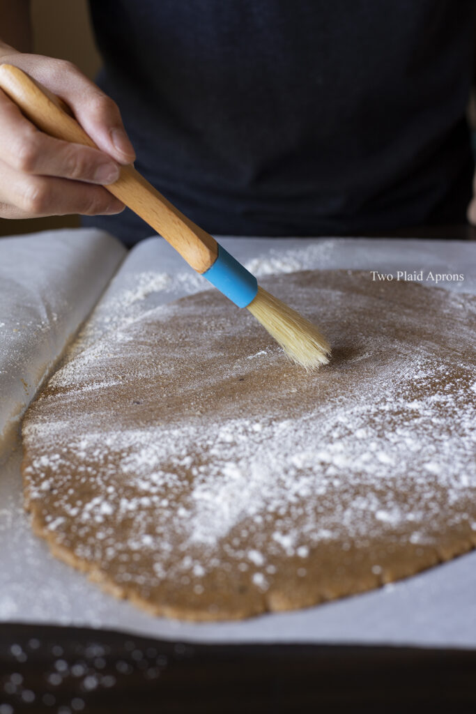 Dusting the rolled out dough with flour and a dry brush.