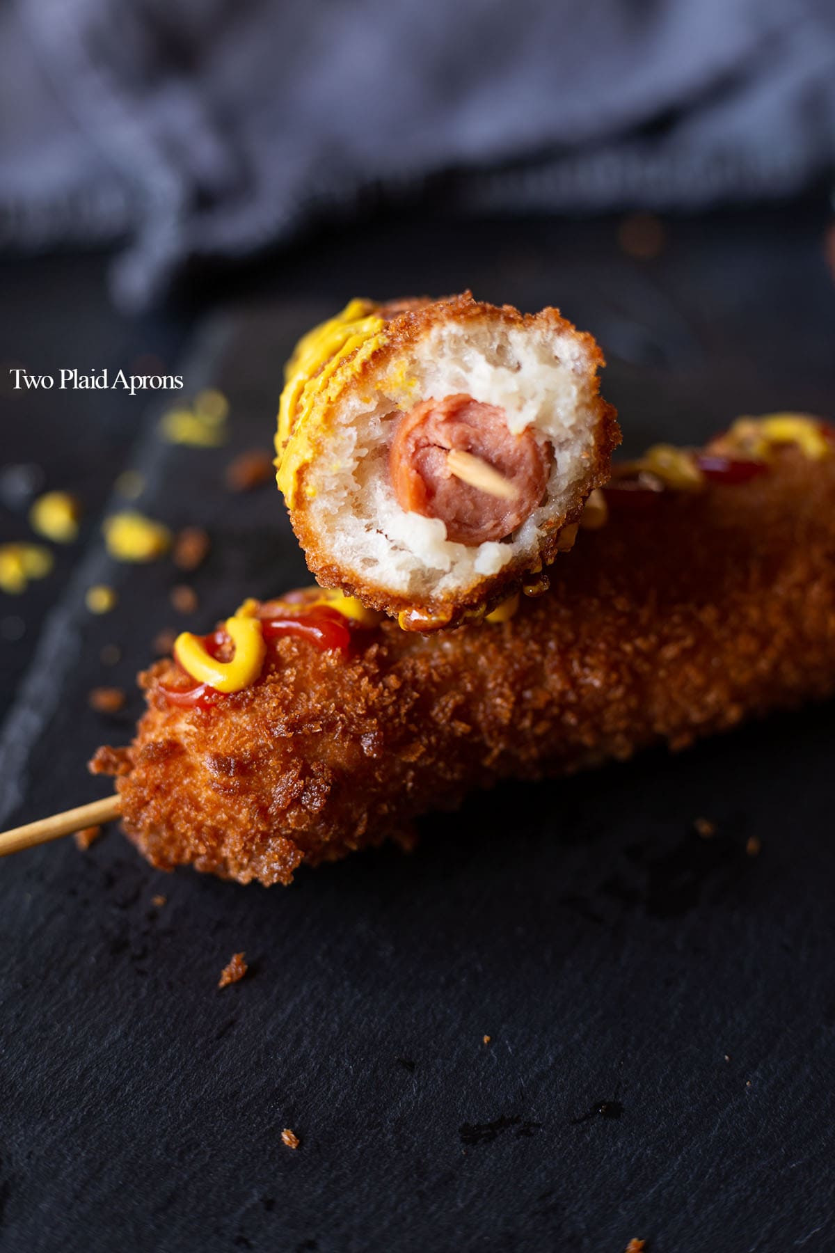 Half of a Korean corn dog leaning on another corn dog.