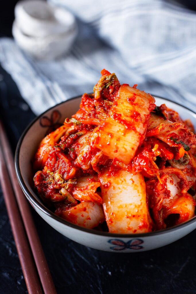 A side angle view of a bowl of fresh kimchi (geotjeori) with chopsticks on the left.
