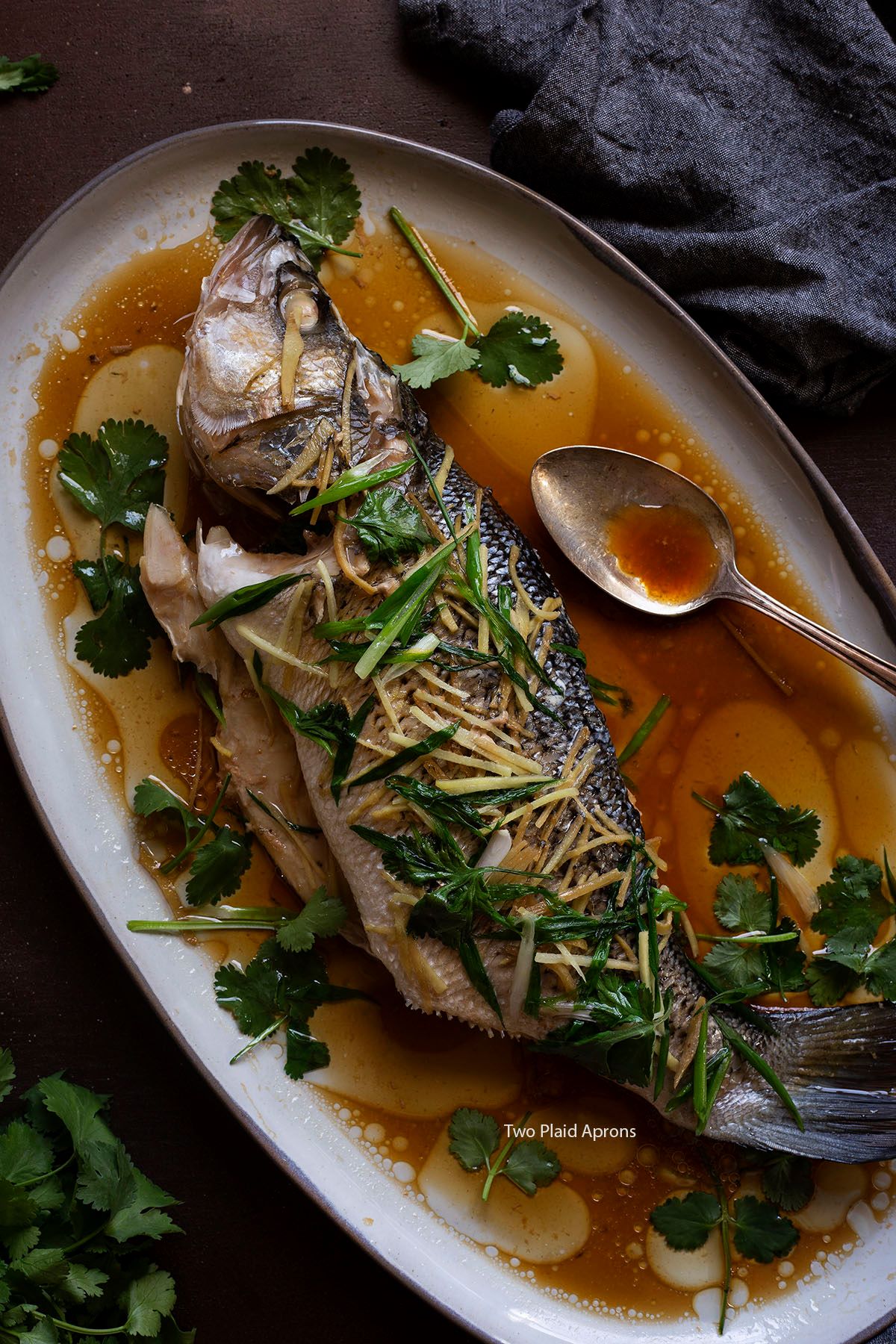 Top view of a whole steamed fish with ginger and scallion.