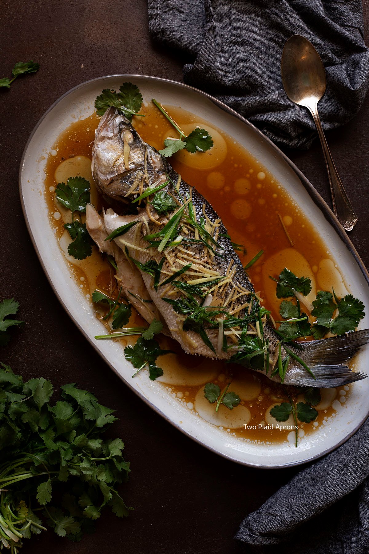Top down view of the Chinese steamed whole fish with ginger and scallion on a platter.