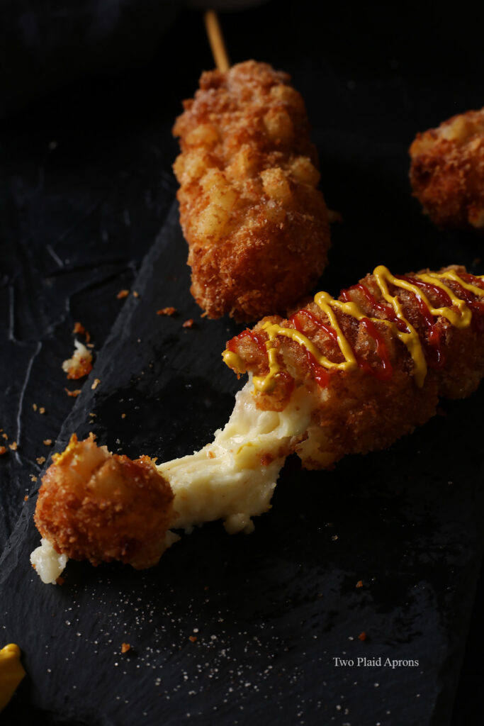 Front view of a Korean french fry corn dog showing a cheese pull.