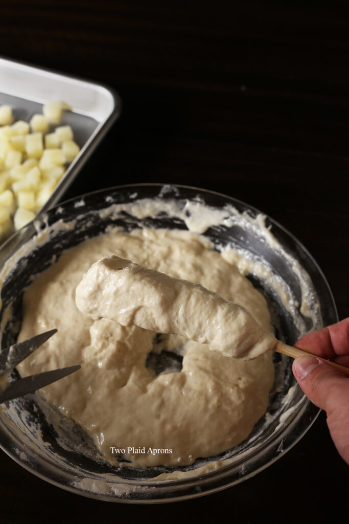 Twisting the dough batter around the corn dog with the help of a pair of scissors.