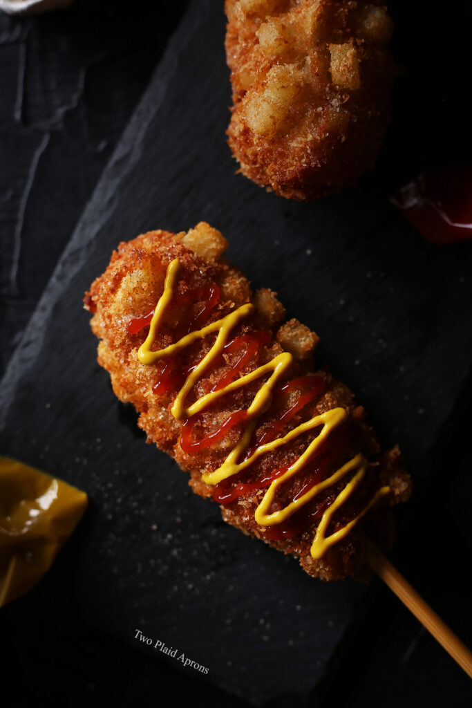 Top down, close up view of Korean french fry corn dog with ketchup and mustard.
