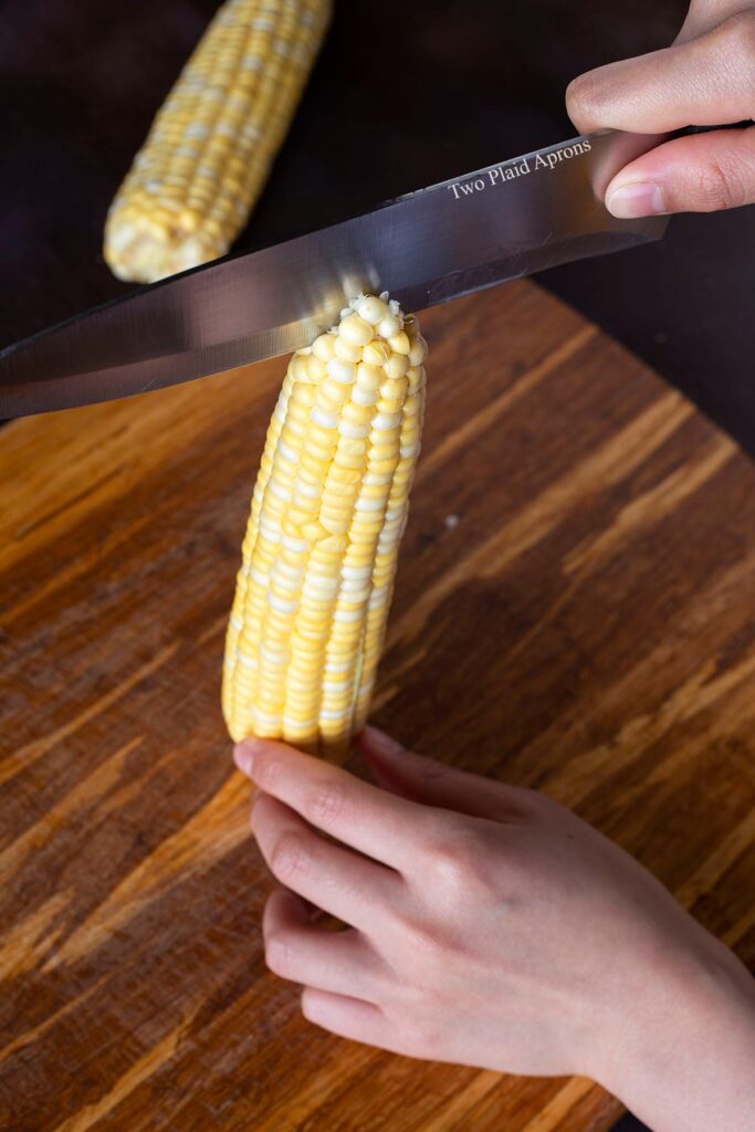 Wedging the blade the the knife into the tip of the corn.