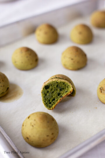 Tray of baked matcha mochi breads with one cut in half.