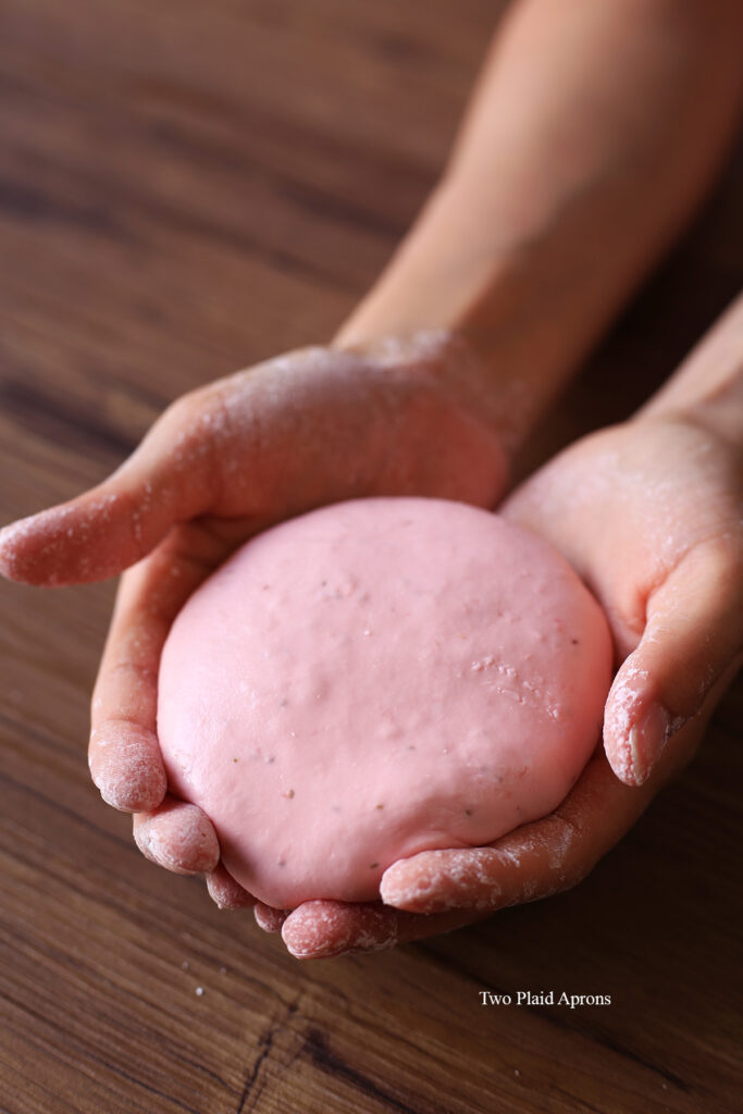 Holding the finished fresh strawberry boba dough in both hands.