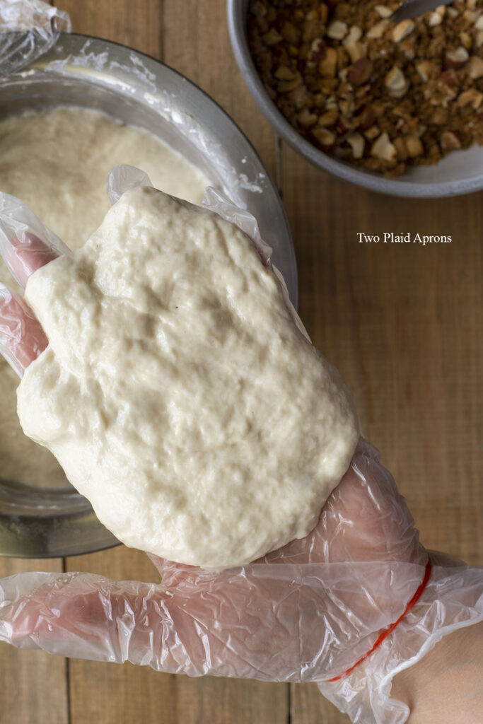 A piece of the dough flattened on gloved hands ready for the filling.