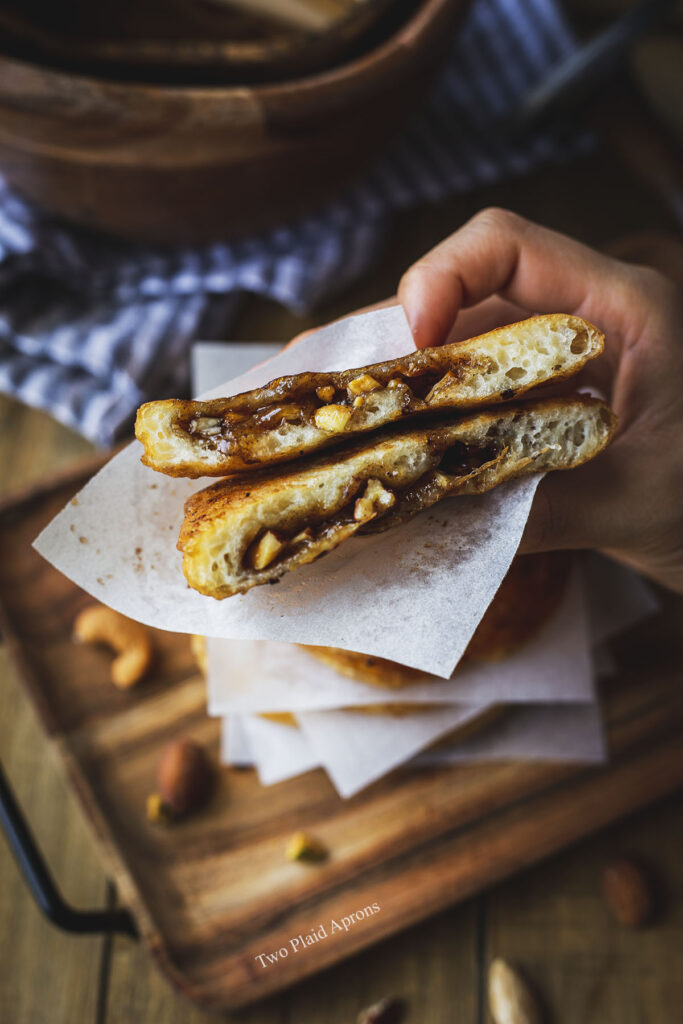 Holding a hotteok cut in half to show the gooey filling.